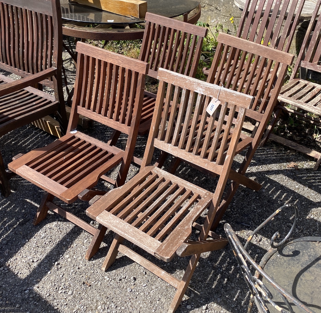 A set of four stained teak folding garden chairs